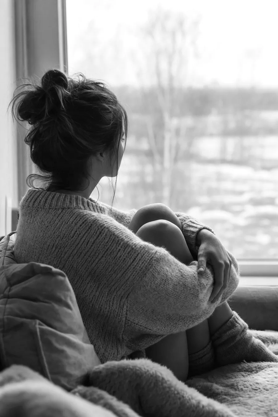 A woman sitting alone by a window, wishing she had answers